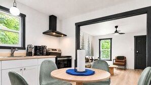 A modern kitchen with a round table, four chairs, a stove, and a black range hood.