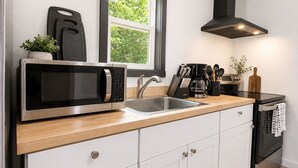 A modern kitchen with a stainless steel microwave, a coffee maker, and a sink.