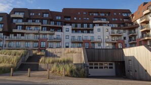 Ein mehrgeschossiges Wohngebäude mit moderner Architektur, mit Balkonen und einem Garageneingang.