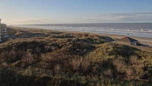 Eine Küstenlandschaft mit Dünen, einem Strand und einem Gebäude mit Dach.