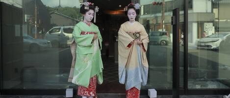 Dos personas vestidas con atuendo tradicional frente a un edificio con puertas de vidrio.