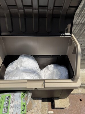 A beige storage bin with a plastic bag inside, placed on a concrete surface. - Ayanishiki Gion (Kyoto)