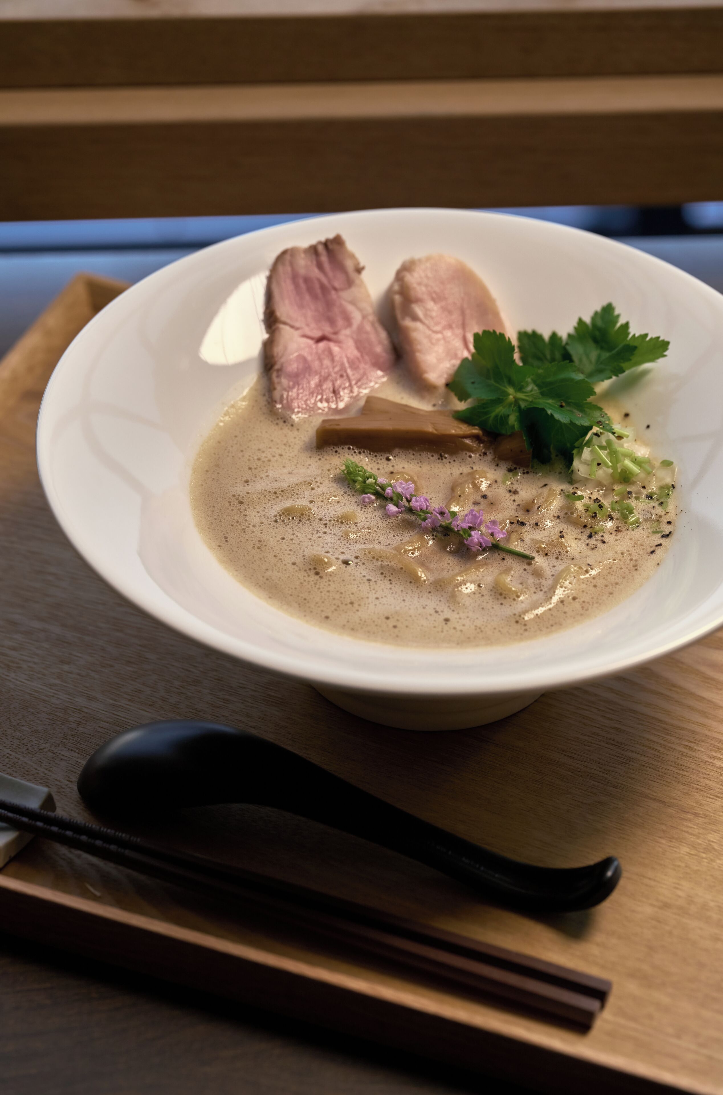 Un tazón de sopa con carne y guarnición sobre una mesa de madera.