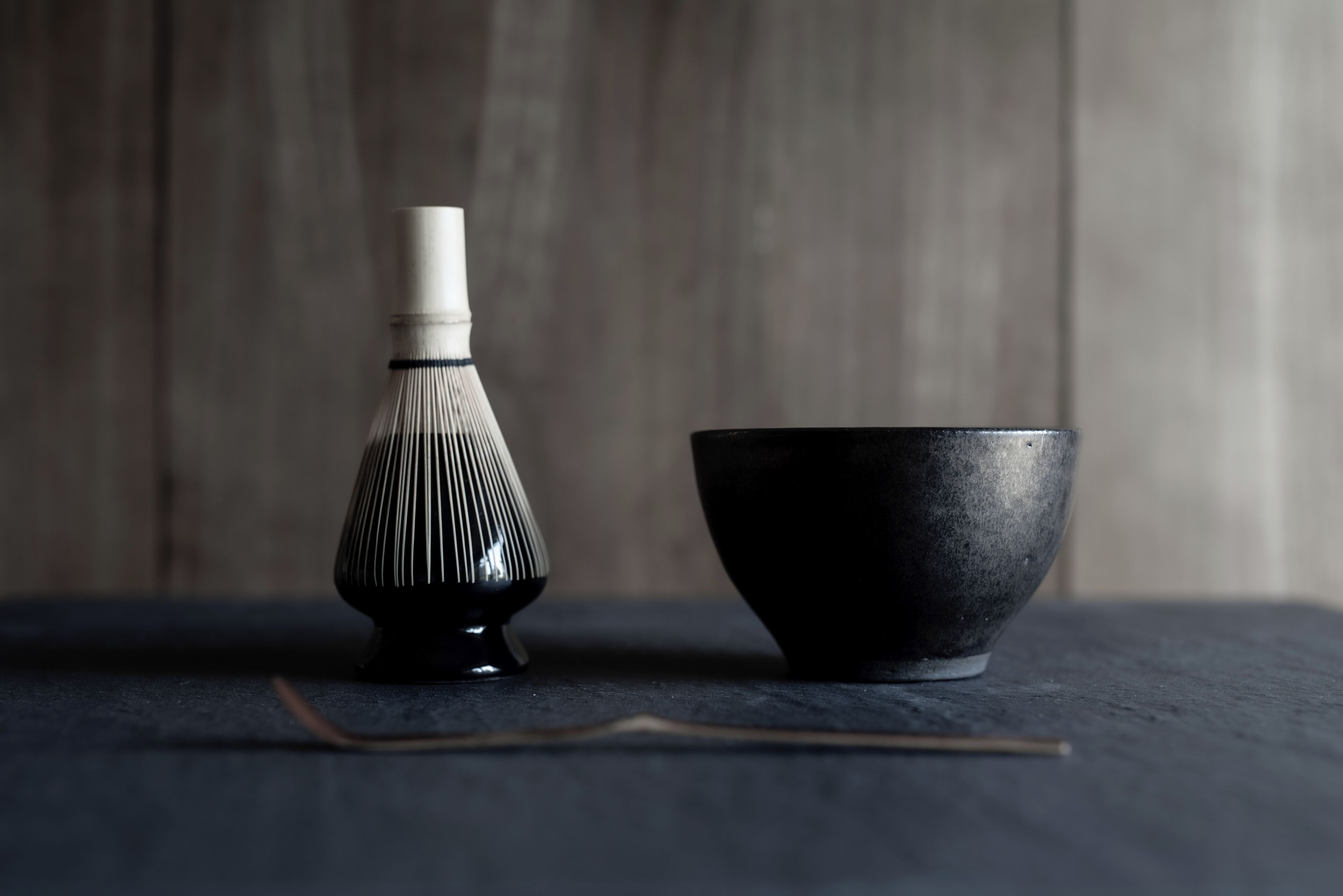 A black bowl and a black bottle with a white cap on a dark surface.