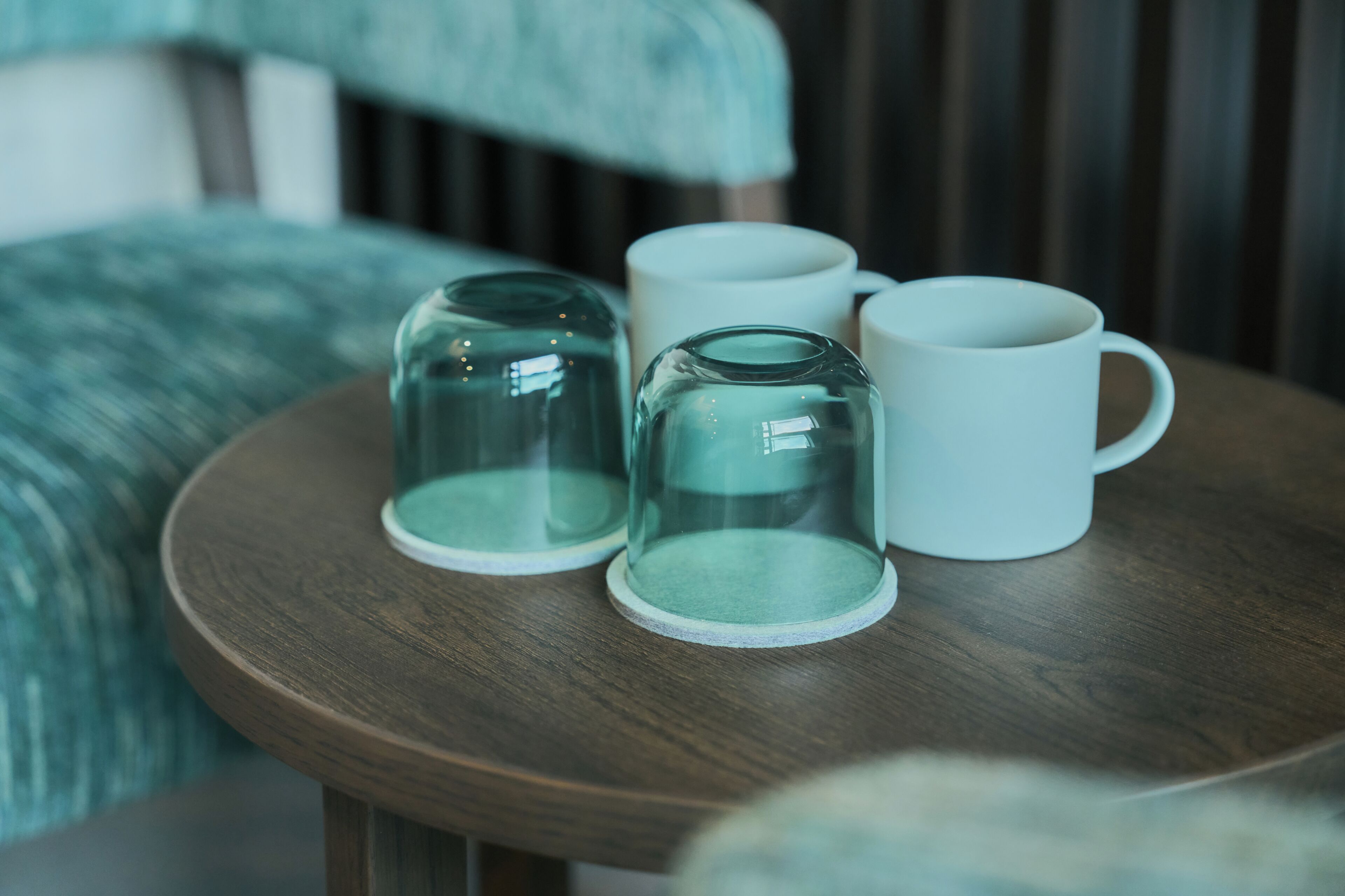 A round wooden table with four glass mugs and a glass carafe.