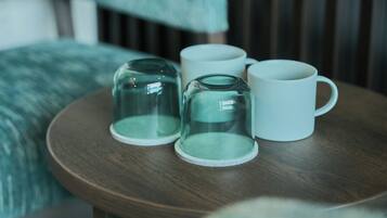 A round wooden table with four glass mugs and a glass carafe.