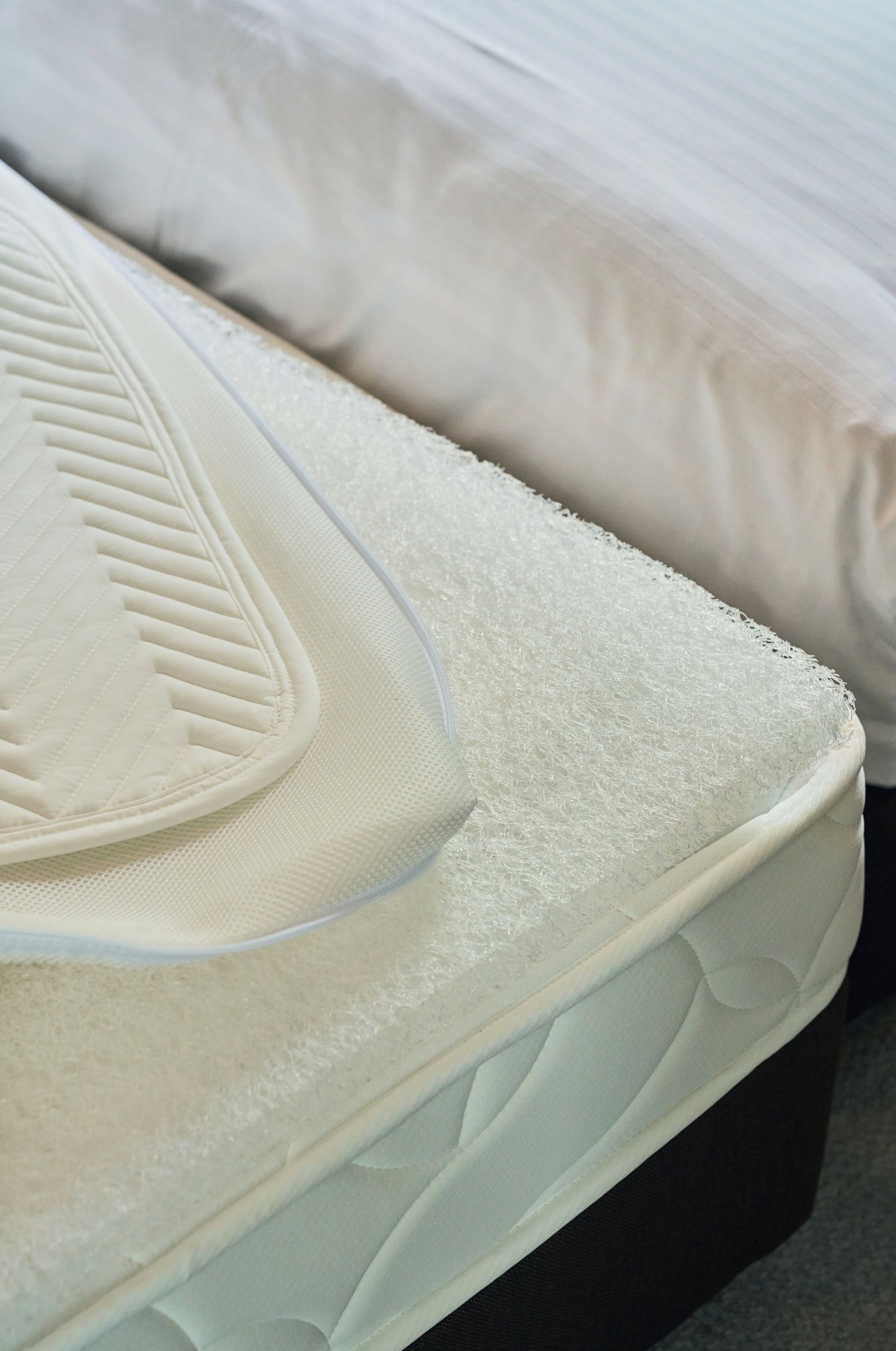 Een detailfoto van een matras met een geribbelde structuur en een zichtbare rits.