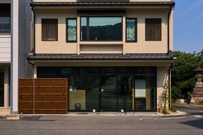 Un edificio de dos pisos con fachada moderna, ventanas grandes y una puerta de madera tradicional.