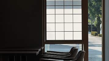 Una habitación con vistas a través de una ventana, una silla y piso de baldosas.