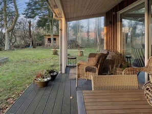 A covered outdoor area with wicker furniture, a table, and a potted plant. - 4 Star Holiday Home in Lokken (Lokken)
