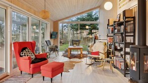 Een gezellige woonkamer met een open haard, een boekenkast en een groot raam met uitzicht op een tuin.
