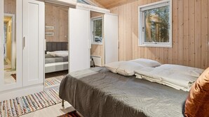 Een kamer met houten lambrisering, een bed, een kast en een raam.