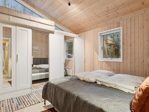 Ein Zimmer mit Holzwänden, einem Bett, einem Kleiderschrank und einem Fenster.