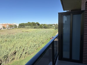Ein Balkon mit Blick auf ein Feld und entfernte Gebäude.