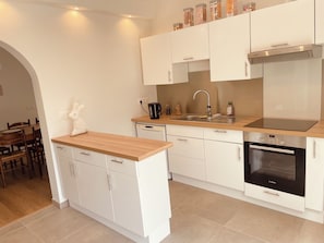 A modern kitchen with white cabinets, a wooden countertop, a Bosch oven, and a sink.