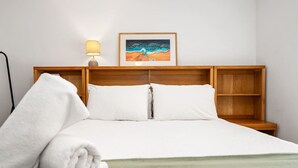A neatly made bed with white linens, a rolled white towel, and a framed painting above the headboard. - Edmund Place – Charming Fremantle Retreat (Fremantle)