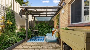 A patio with a pergola, a small table, and a blue bean bag chair. - Edmund Place – Charming Fremantle Retreat (Fremantle)