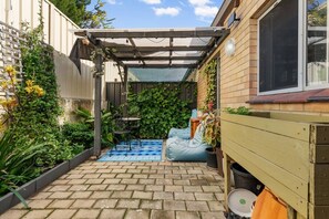 A patio with a pergola, a small table, and a blue bean bag chair. - Edmund Place – Charming Fremantle Retreat (Fremantle)