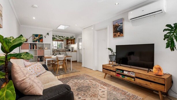 A modern living room with a sofa, TV, and a dining area with chairs and a table. - Edmund Place – Charming Fremantle Retreat (Fremantle)