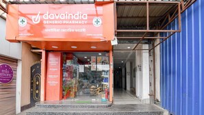 Apteekki nimeltä ”davaindia generic pharmacy”, jonka yläpuolella on useilla kielillä oleva kyltti, ja jossa on lasiovet ja portaat, jotka johtavat sisäänkäynnille.