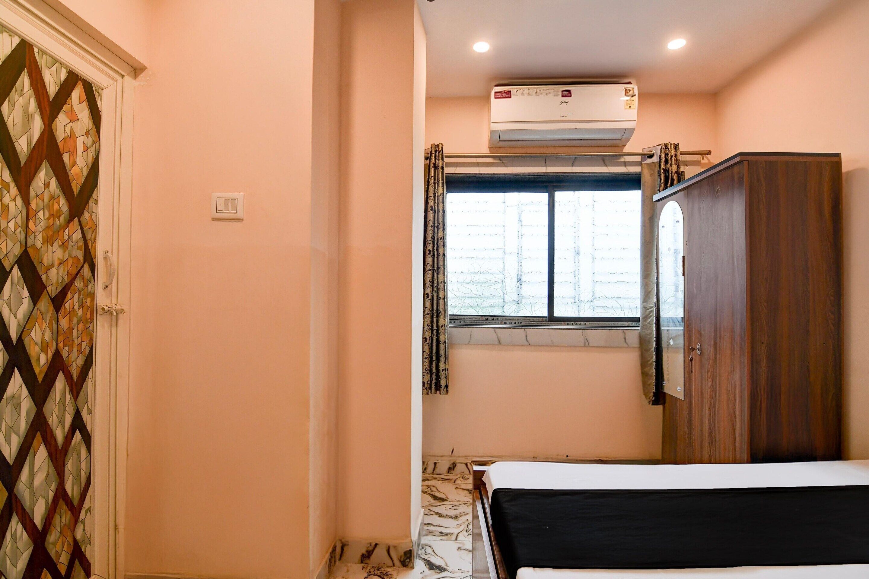 A bedroom with a bed, a wardrobe, a window with curtains, and an air conditioning unit.