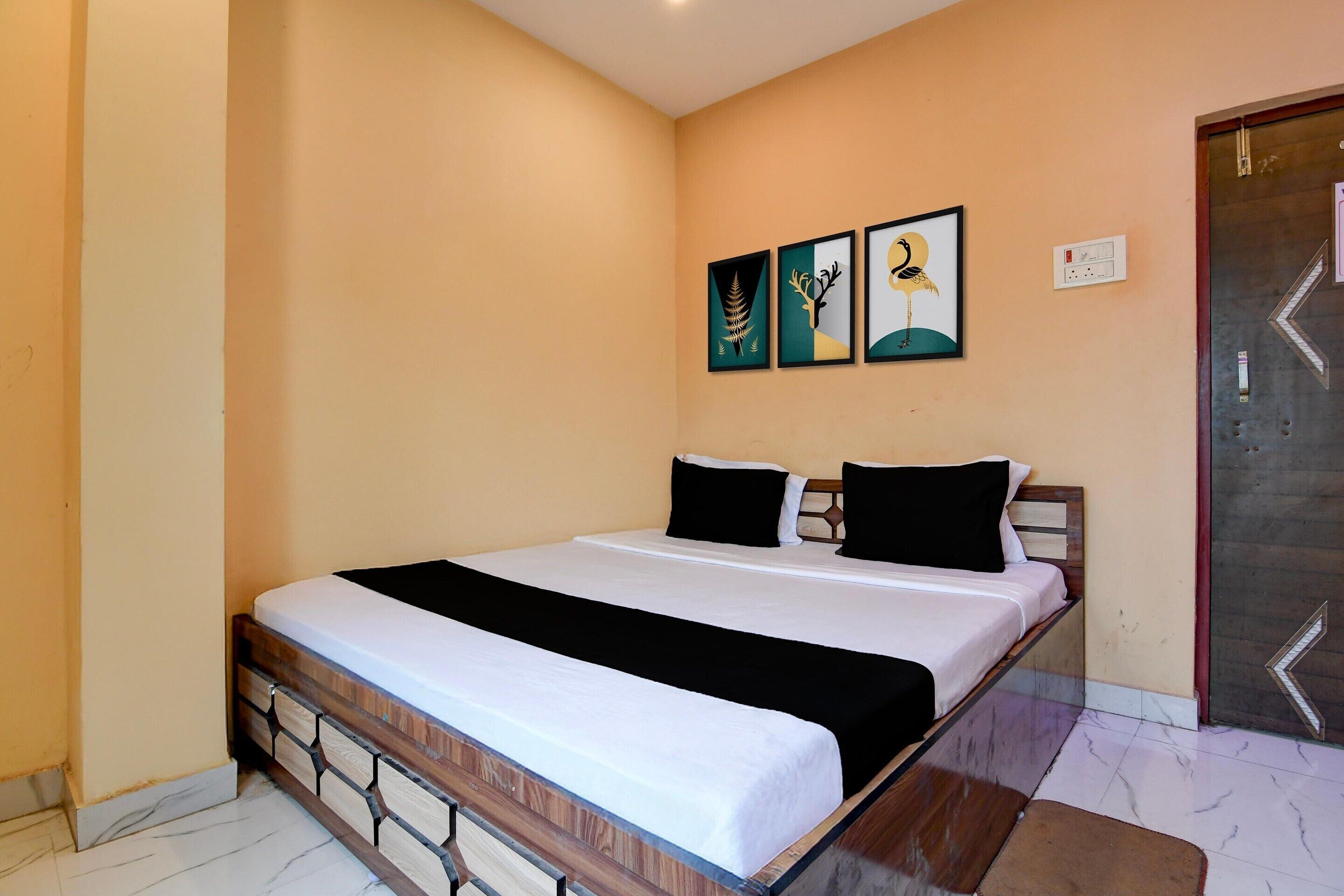 A bedroom with a bed, a wooden headboard, a marble floor, and three framed artworks on the wall.