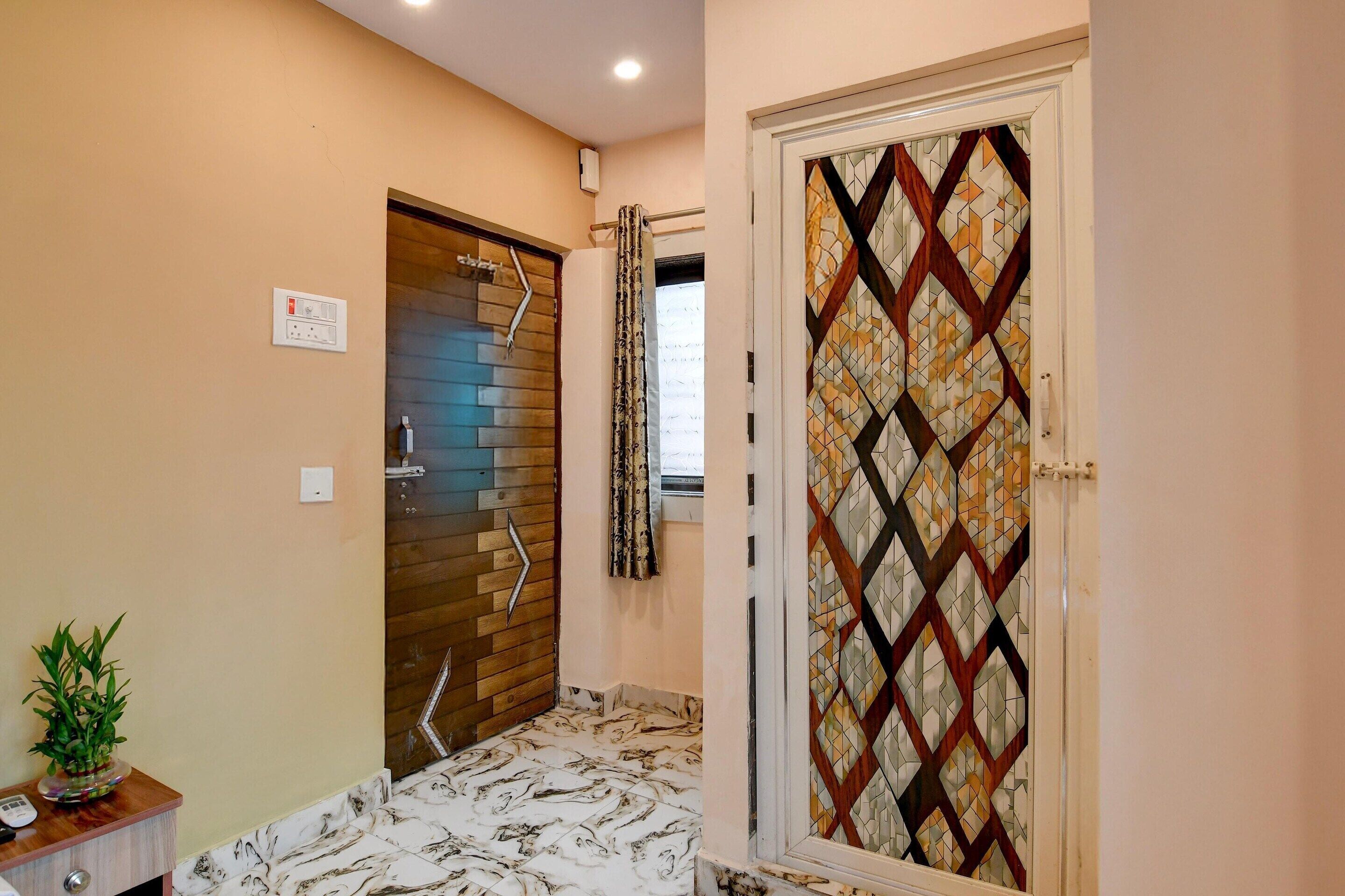 A bathroom with a marble floor, a wooden door, and a glass door with a geometric pattern.