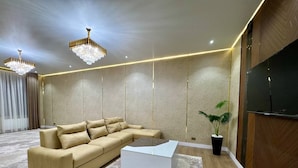 Una sala de estar moderna con un sofá modular, una mesa de centro, una planta en maceta y un televisor de pantalla plana.