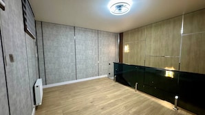 Una habitación moderna con suelo de madera, paredes grises y un panel de vidrio.