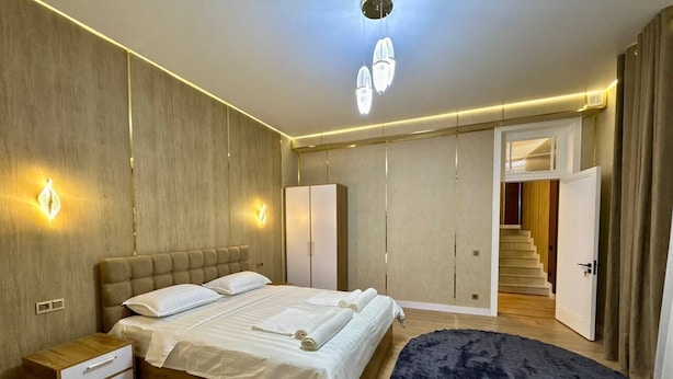 Un dormitorio con cama, mesitas de noche, un armario y una escalera que lleva a otra habitación.