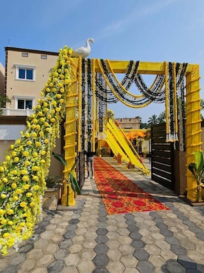 A decorated entrance with a yellow archway, a white swan sculpture, and a floral arrangement. - Mahamaya Convention And Hotel (Puri)