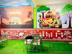 Un mural amb escenes tradicionals, una zona de menjador amb caires i una taula.