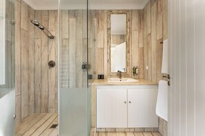 A bathroom with a glass shower enclosure, a wooden wall design, a sink with a mirror, and a white cabinet. - Serene Suite w/ Balcony & Ocean View, Perfect for a Quiet Retreat (Lagos)