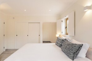 Ett hotellrum med en stor säng, en garderob, en spegel och en liten sittgrupp.