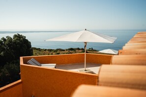 A balcony with a white umbrella, a view of the sea, and a wooden railing. - Minimalist Oasis w/ King Bed & Stunning Garden View Near Luz Beach (Lagos)