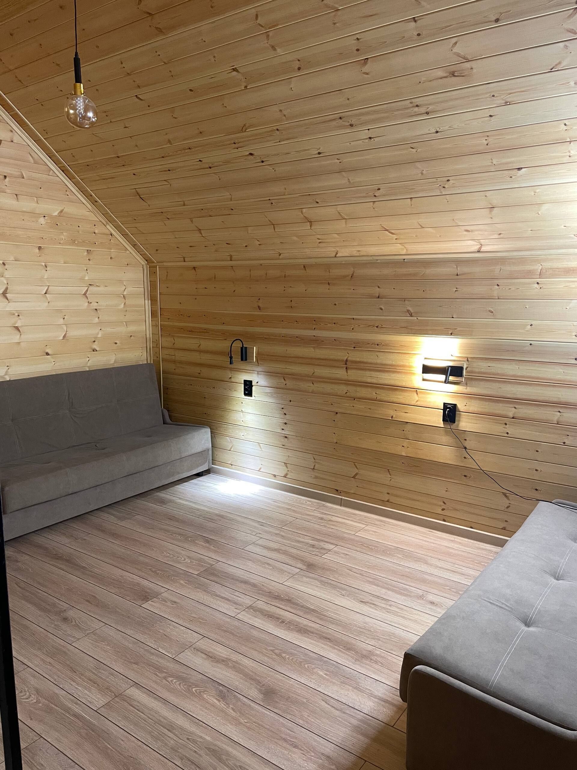 Ett rum med väggar beklädda med träpaneler, en soffa, en bänk och två väggmonterade lampor.