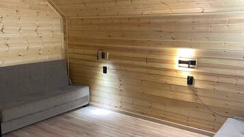 Et værelse med træpaneler, en sofa, en bænk og to vægmonterede lamper.
