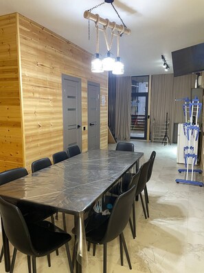 A conference room with a marble table, black chairs, wooden panel walls, and a ceiling-mounted light fixture.
