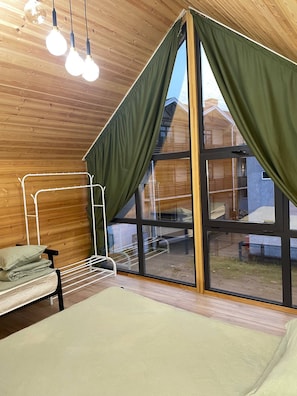 Una habitación con una cama, una ventana con cortinas e iluminación colgante.