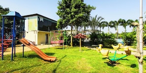 Un parque infantil con tobogán, columpios y balancines.