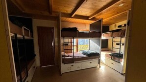 Una habitación pequeña con literas, techo de madera y ventana con vistas.