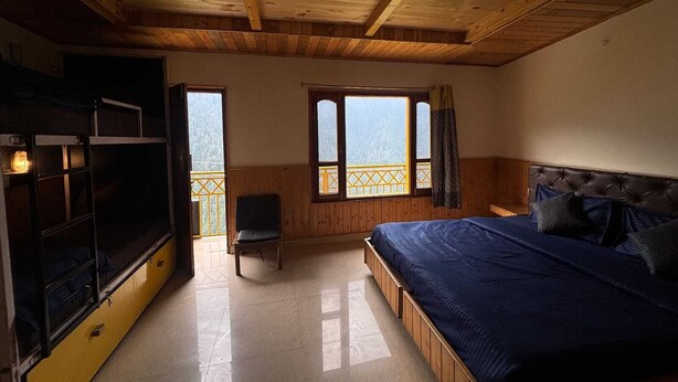 Una habitación con cama, una silla, televisión y ventana con vistas.