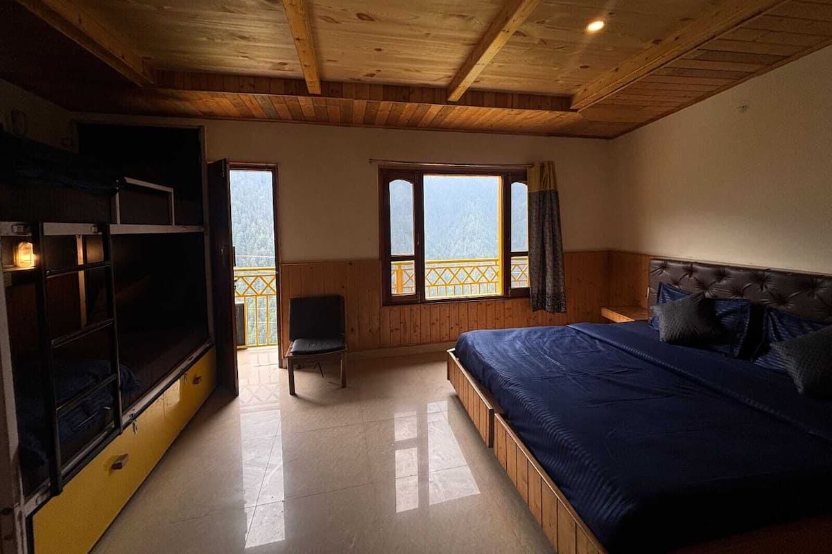 Una habitación con cama, una silla, televisión y ventana con vistas.