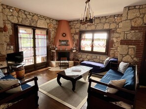 Ein gemütliches Wohnzimmer mit Steinwänden, einem Kamin, einem Fernseher und bequemen Sitzmöglichkeiten.