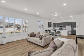 A modern living room with a sofa, a dining table, and a kitchen area with cabinets and appliances. - Timpanogos View Retreat with RV Parking Pad (Heber City)