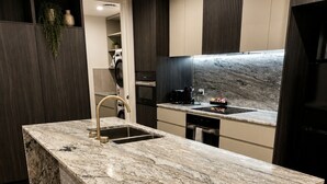 A modern kitchen with a marble island, dark wood cabinetry, and a built-in oven. - Relaxing 2BR with Lake Views in Eastbourne (Parkes)