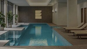 An indoor swimming pool with lounge chairs and potted plants. - Relaxing 2BR with Lake Views in Eastbourne (Parkes)