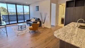 A modern living room with a sofa, coffee table, and a view through large windows. - Relaxing 2BR with Lake Views in Eastbourne (Parkes)
