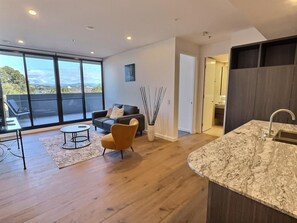 A modern living room with a sofa, coffee table, and a view through large windows. - Relaxing 2BR with Lake Views in Eastbourne (Parkes)
