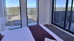 A hotel room with a large bed, a view of the landscape, and a balcony with chairs. - Relaxing 2BR with Lake Views in Eastbourne (Parkes)